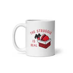 a white coffee mug with the words, the struggle is real and a santa hat