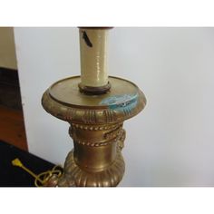 a candle is sitting on top of a gold pillar with a blue bird painted on it