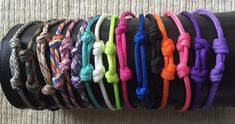 a bunch of different colored ropes on a black leather armband, all tied together