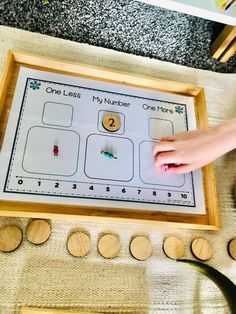 a child's hand is playing with a number matching game in front of wooden circles