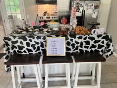 a cow print table cloth is on top of two stools in front of the counter