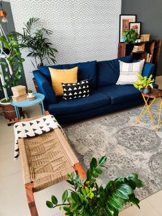 a living room with blue couches and potted plants on the table in front of it