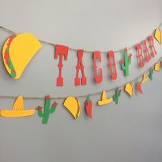 a taco bar banner hanging from a string with paper cutout letters and hats on it