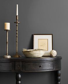 a table with a bowl and candles on it next to a framed photograph, candle holder and other items