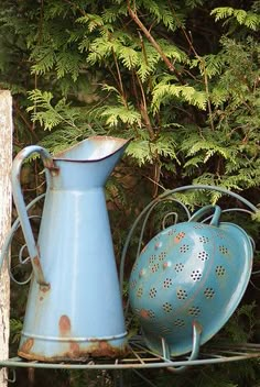 two blue vases sitting next to each other on a metal shelf in front of trees