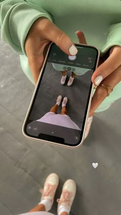 a woman is holding up her cell phone while she's wearing white slippers