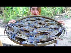 a woman holding a basket full of blue crabs