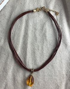 "You will receive his pretty glass bead and leather necklace from Lia Sophia. The leather measures 16\" with a 3\" chain extender and there are 8 strands. The orange striped glass bead pendant measures 1 3/4\" x 5/8\" and is attached to the leather with a gold tone base metal connector. It is signed on the hang tag. This necklace is in very good vintage condition with minimal signs of wear. For finished vintage assemblage and vintage inspired necklaces, bracelets, and earrings, please visit us a Brown Leather Necklace With Adjustable Length, Brown Multi-strand Necklace Gift, Brown Leather Pendant Necklace, Adjustable Brown Glass Necklace, Adjustable Brown Teardrop Jewelry, Brown Glass Necklace For Gift, Adjustable Brown Necklaces, Elegant Brown Necklace With Adjustable Cord, Adjustable Amber Glass Necklaces