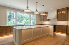 an empty kitchen with wooden cabinets and white counter tops in front of a large window