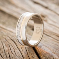 a wedding ring with antler wood inlays on the outside of it, sitting on a wooden surface