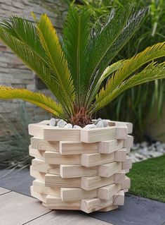 a planter made out of wooden blocks with a pine tree in the center and rocks on top