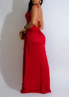 a woman in a long red dress is holding a purse and posing for the camera