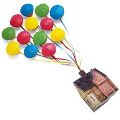 a bunch of colorful balloons flying over a house on top of a pile of money