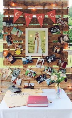 a table topped with pictures and books under a string of lights next to a wooden wall