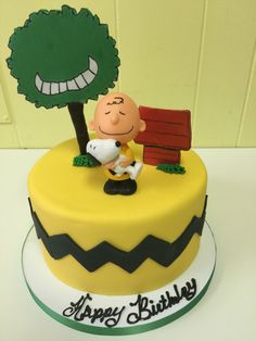 a birthday cake with a charlie the pooh figure on top and a tree in the background