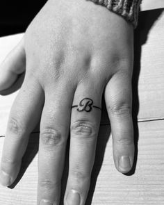 a woman's hand with a small black and white tattoo on her left ring finger