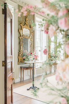 a table with flowers on it in front of a mirror and some mirrors behind it