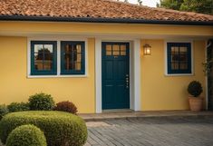 a yellow house with two blue doors and green shutters on the front door is shown