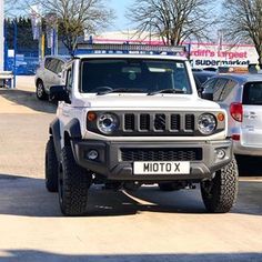 a white jeep is parked in front of other cars