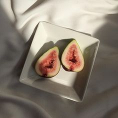 two pieces of figs on a white plate sitting on a bed with the sheets pulled back