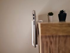 a white refrigerator freezer sitting on top of a wooden cabinet next to a potted plant