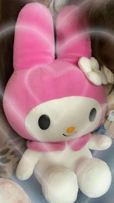 a pink hello kitty stuffed animal sitting on top of a bed