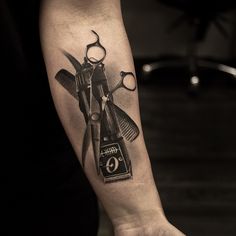 a tattoo with scissors and combs on the left arm is shown in black and white