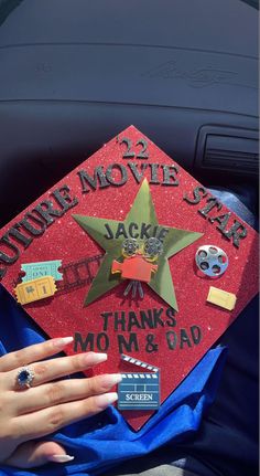 a woman's hand on top of a red graduation cap that reads 25 movie star jacks, thanks mom & dad