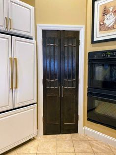 a kitchen with two ovens and a microwave in it's center, next to a doorway leading into another room