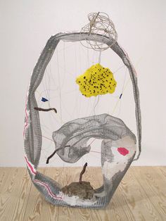 a wire sculpture with an animal inside of it on top of a wooden floor next to a white wall