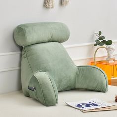 a green reclining chair sitting on top of a white table next to a plant