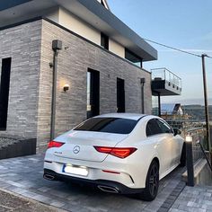 a white car is parked in front of a building with a balcony and balconies