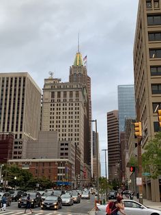 a busy city street with tall buildings and cars driving down the road in front of it