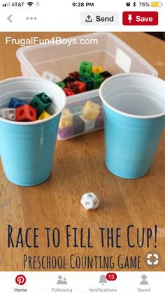 two cups filled with legos sitting on top of a table next to a game