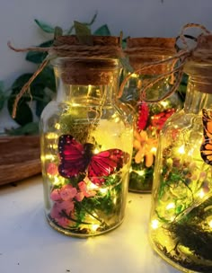 three glass jars with fairy lights and butterflies in them