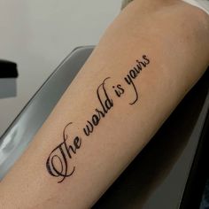 a tattoo saying the world is yours on someone's arm