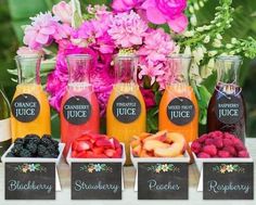 a table topped with bottles of juice and containers filled with fruit sitting next to each other