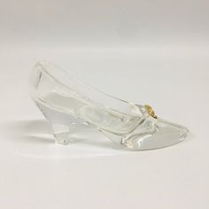 a clear shoe with a gold buckle on the heel