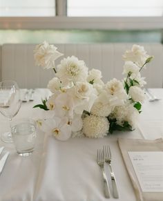 a table with white flowers and silverware on it