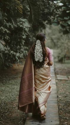 a woman in a sari walking down a path with her hair combed back