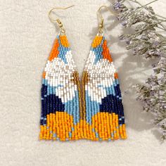 a pair of colorful beaded earrings sitting on top of a table next to flowers