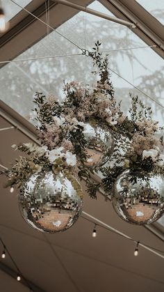 three disco ball vases filled with flowers hanging from the ceiling