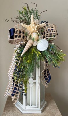 a lantern decorated with seashells, greenery and starfish for the centerpiece