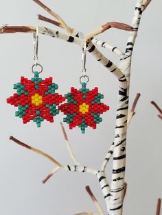 a pair of earrings made out of legos hanging from a tree branch with birch branches in the background