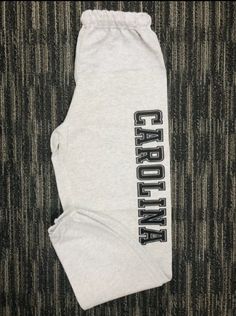 College Sweatpants Personalized | College Apparel | College Apparel Custom College name printed down left leg. Print Size 16x3in. 1 color Unisex Sweatpants - 973MR 8 oz., pre-shrunk 50/50 cotton/polyester Oxford is 49/51 cotton/polyester NuBlend pill-resistant fleece High stitch density for a smooth printing canvas No side seams Double-needle stitched covered waistband with inside drawcord Elastic bottom leg openings Casual Cotton Pants With Logo Print, Sports Cotton Pants With Logo Print, Casual Stretch Bottoms With Logo Print, Stretch Cotton Pants With Letter Print, Sporty Stretch Bottoms With Logo Print, Gray Letter Print Athleisure Pants, Gray Athleisure Pants With Letter Print, Sports Cotton Pants With Letter Print, Casual Cotton Bottoms For College