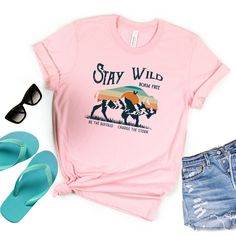 Looking for a tee that will make you stand out? This stay wild graphic tee is perfect for you! Made from ultra-soft material, with an eye-catching buffalo design, this comfortable and stylish top is sure to get you noticed. Roam free and stay wild! Summer Adventure T-shirt With Text Print, Summer Adventure Graphic Print T-shirt, Trendy Graphic Print Tops For Outdoor Activities, Trendy Outdoor Relaxed Fit T-shirt, Trendy Relaxed Fit T-shirt For Outdoor, Trendy Outdoor Graphic Print T-shirt, Casual T-shirt With Funny Print For Outdoor Activities, Pink Graphic Print Top For Outdoor, Buffalo Design