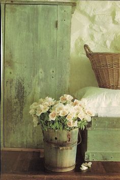 a basket with flowers sitting on top of a wooden table next to a green door