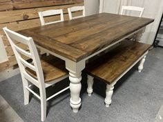 a wooden table and two white chairs in a room