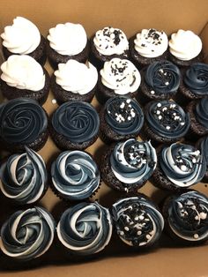 a box filled with lots of blue and white cupcakes