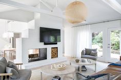 a living room filled with furniture and a flat screen tv mounted on the wall above a fire place